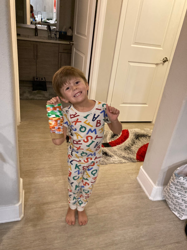 Child wearing colorful pajamas with letters in a room.