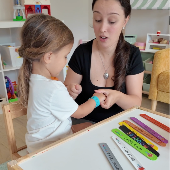 Woman and child interacting at a table with educational tools in a classroom setting