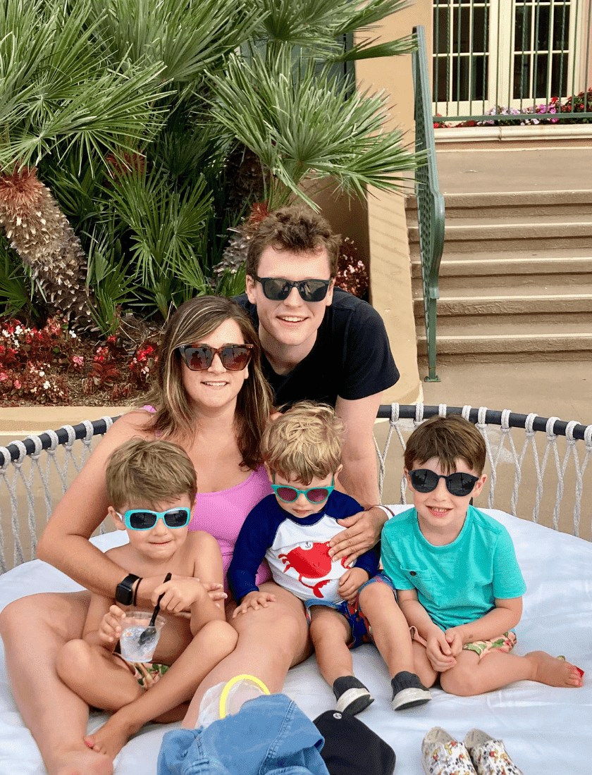 Family of five with sunglasses posing on a bed outdoors.