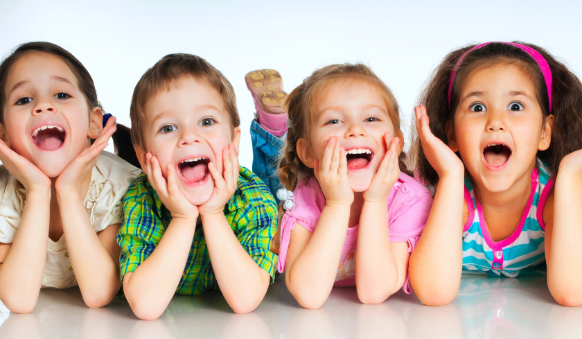 Four children lying on a white surface with a light blue gradient background